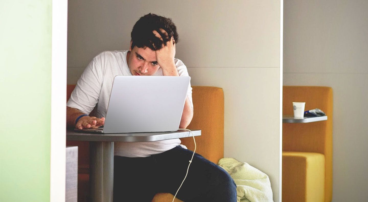 Bilde av en mann som ser sliten ut foran en laptop