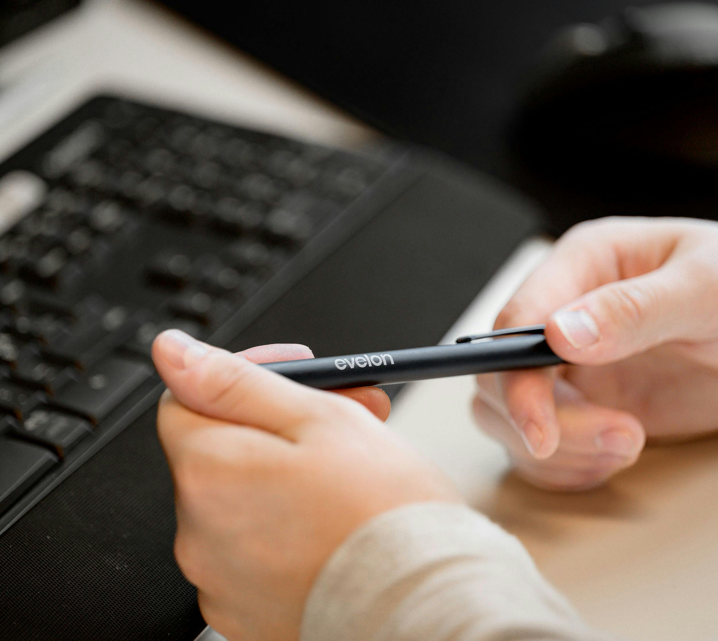 Bilde av hender som holder en penn og et tastatur