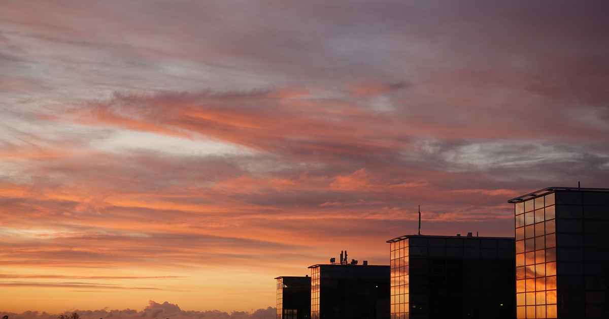 Bilde av solnedgang med høye bygninger på høyre side